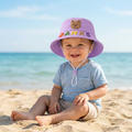Happy toddler wearing the personalized lavender teddy-bear bucket sun hat on a sunny beach